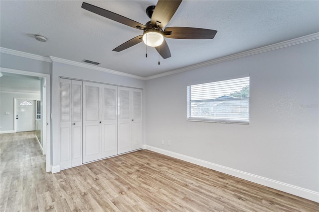 unfurnished bedroom featuring a textured ceiling, light hardwood / wood-style flooring, a closet, crown molding, and ceiling fan