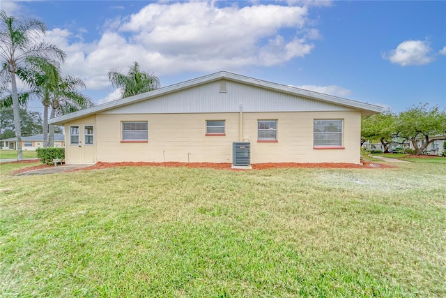 view of side of property with a yard and central AC