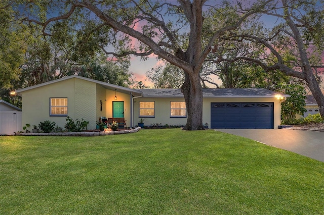 ranch-style house with a garage and a yard