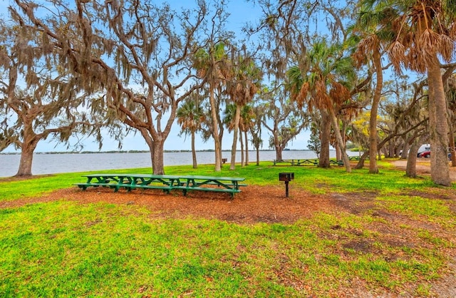 surrounding community with a water view and a lawn