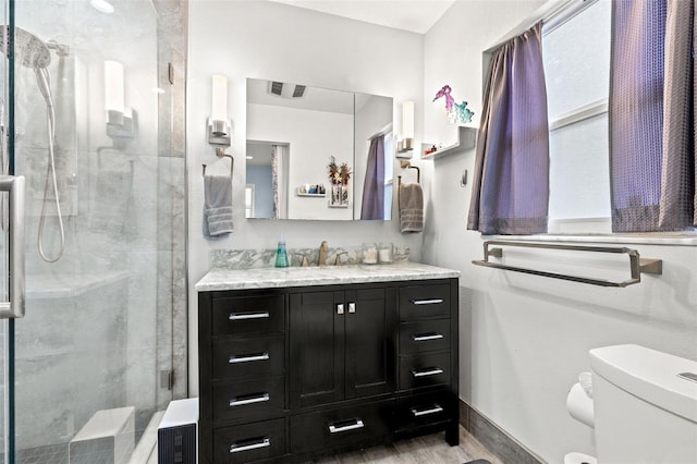 bathroom with baseboards, toilet, wood finished floors, vanity, and a shower stall