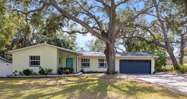 ranch-style home featuring driveway, brick siding, an attached garage, and a front yard