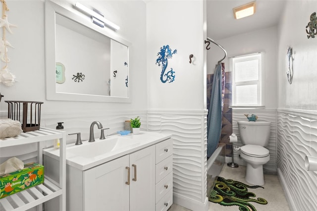 bathroom featuring shower / tub combo, a wainscoted wall, vanity, and toilet