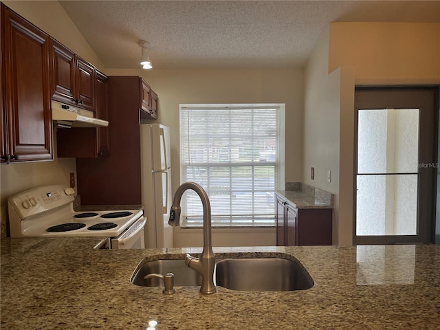 kitchen with a textured ceiling, light stone countertops, sink, and white appliances