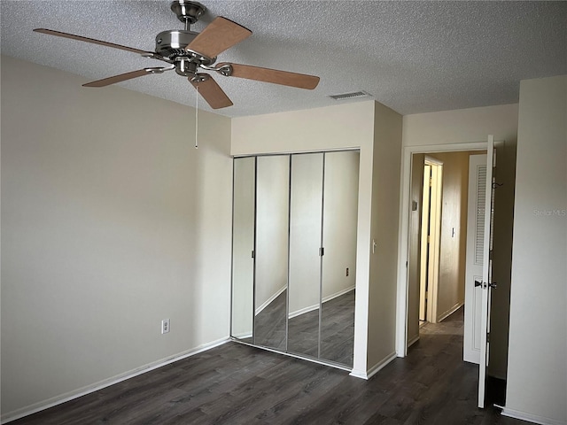 unfurnished bedroom featuring ceiling fan, a closet, dark hardwood / wood-style floors, and a textured ceiling