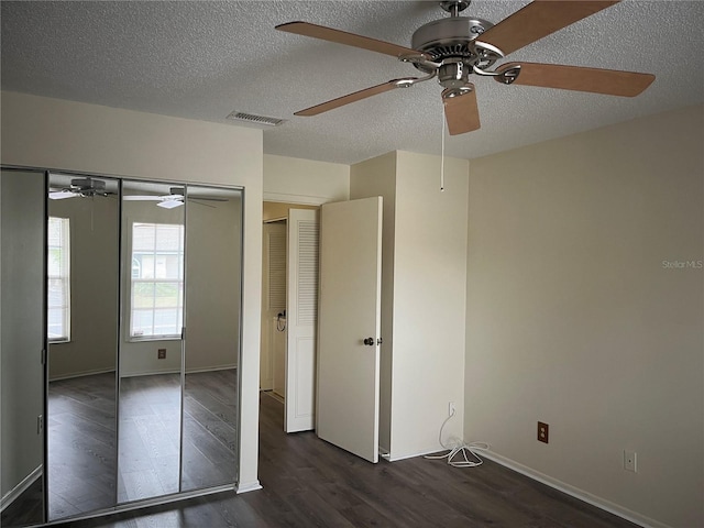 unfurnished bedroom with dark wood-type flooring, ceiling fan, a closet, and a textured ceiling