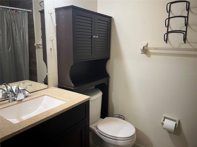 bathroom featuring toilet, vanity, and curtained shower