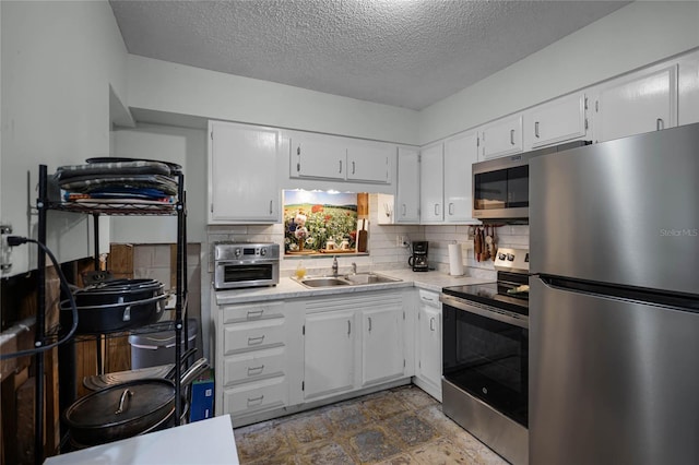 kitchen featuring a textured ceiling, stainless steel appliances, tasteful backsplash, white cabinets, and sink