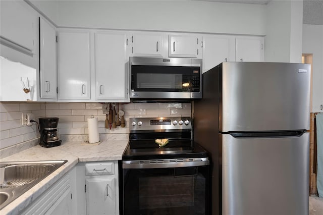 kitchen with stainless steel appliances, white cabinets, and decorative backsplash