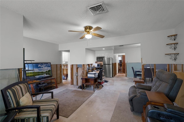 living room featuring ceiling fan and a textured ceiling