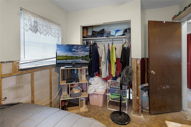 bedroom with a closet, parquet flooring, and a textured ceiling