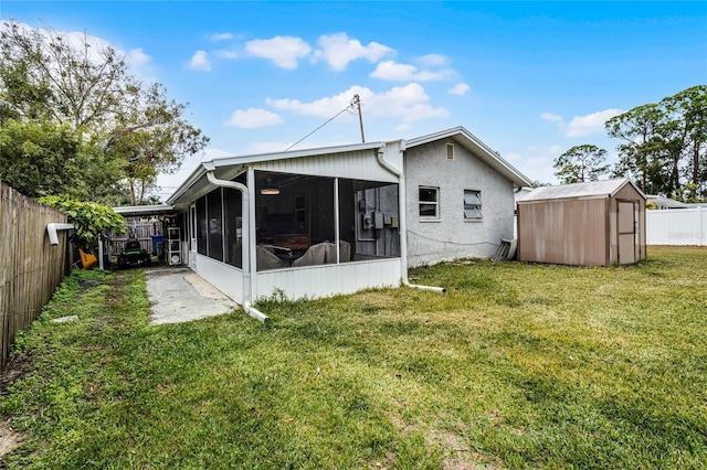 rear view of property with a lawn, a sunroom, and a storage shed