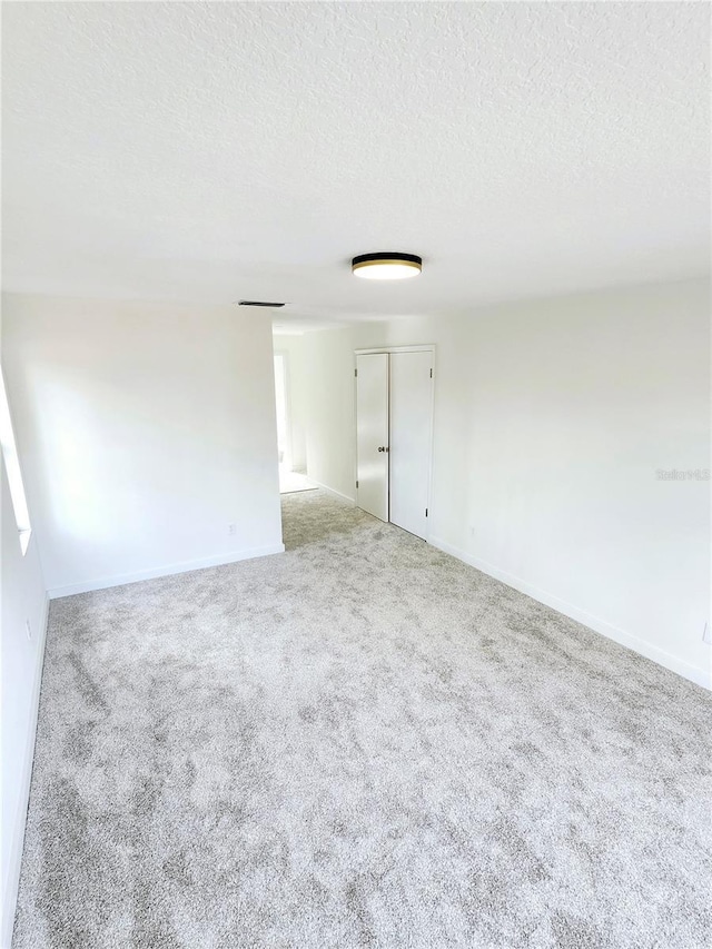 carpeted spare room featuring a textured ceiling