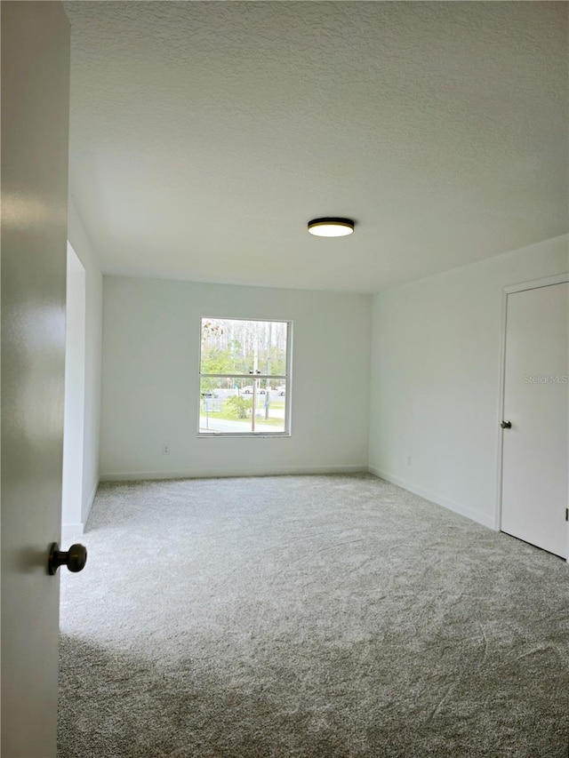 carpeted empty room featuring a textured ceiling