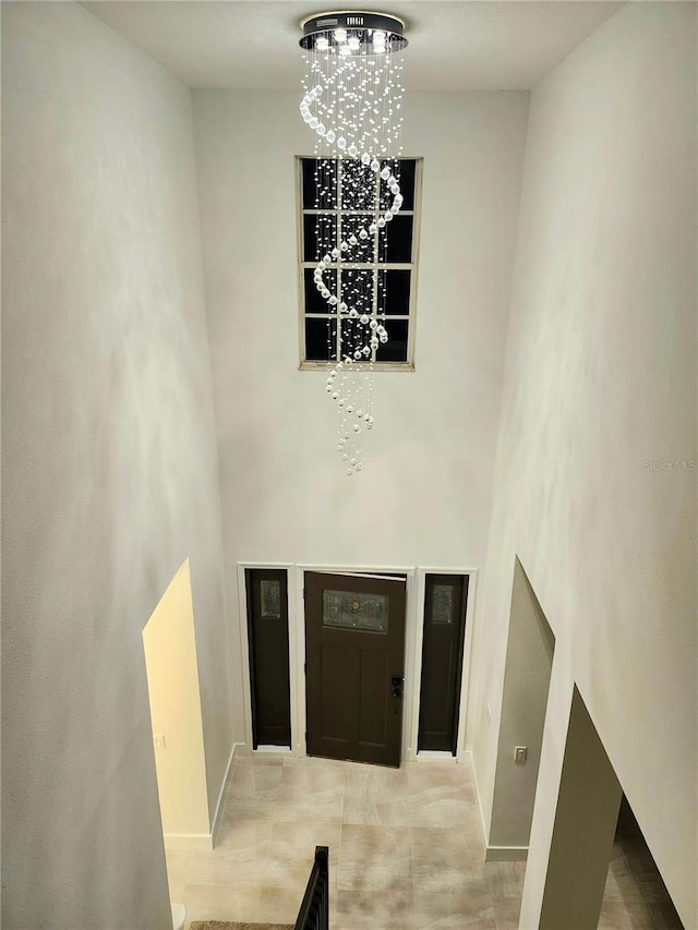 entrance foyer with baseboards, a towering ceiling, and an inviting chandelier