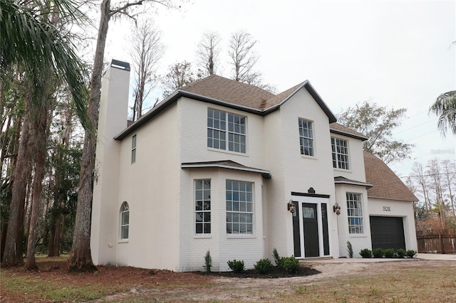 traditional-style house with brick siding, a chimney, and an attached garage