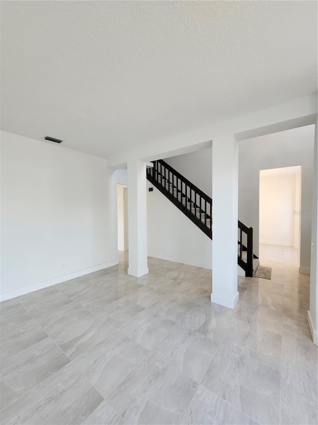 interior space with stairs, a textured ceiling, visible vents, and baseboards