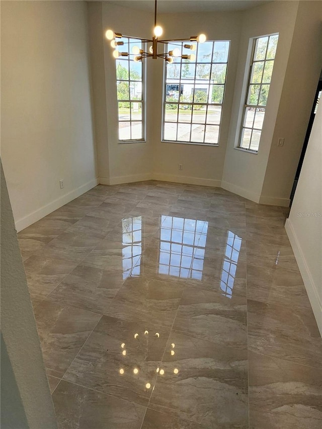 unfurnished dining area featuring a healthy amount of sunlight, marble finish floor, and baseboards