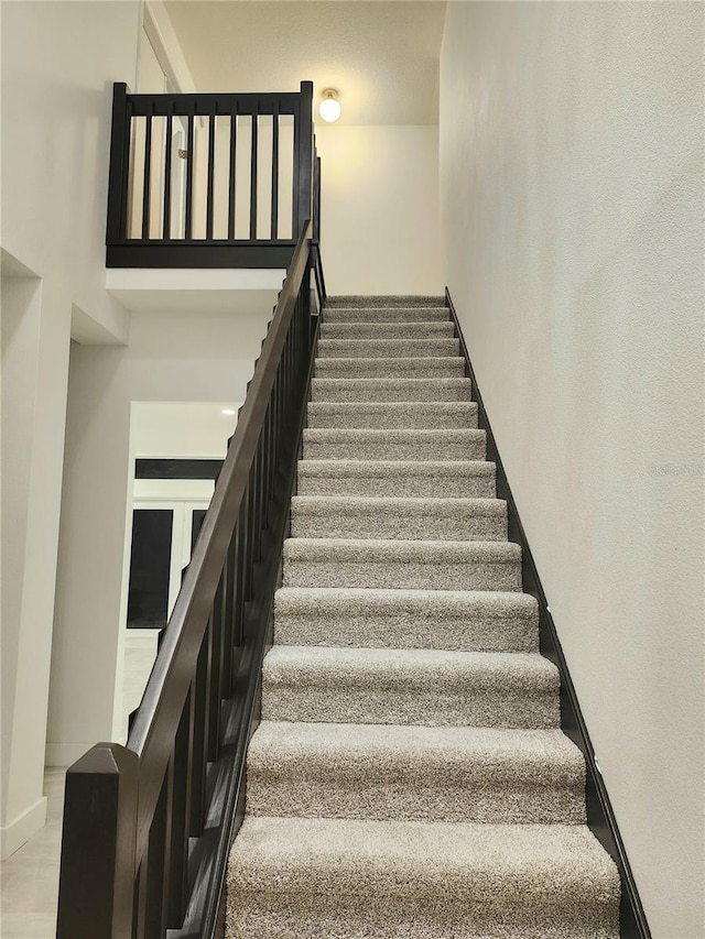 stairs featuring a high ceiling and baseboards