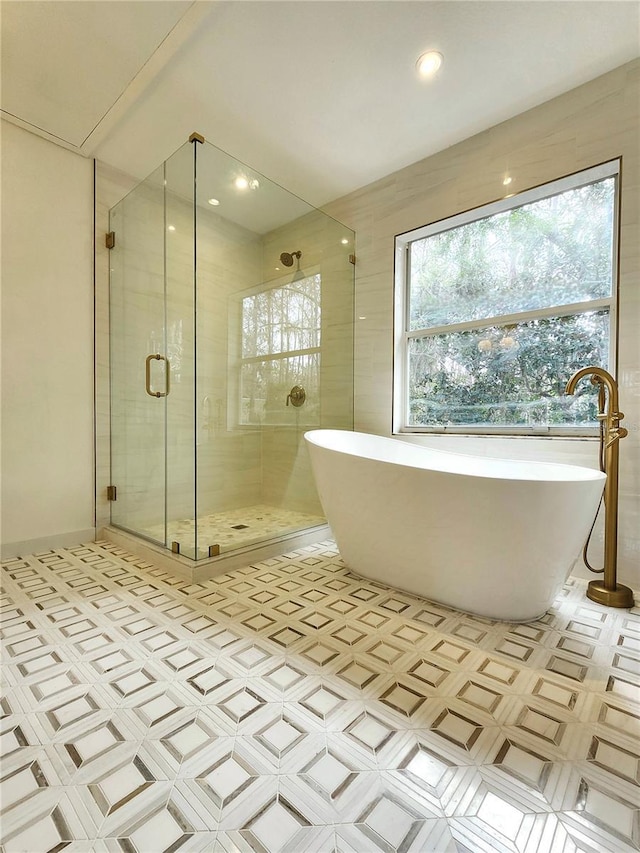 full bath with tile patterned flooring, a soaking tub, and a shower stall