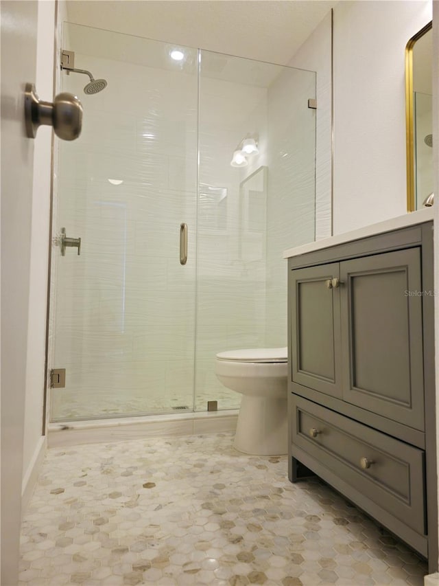 full bathroom featuring a stall shower, vanity, and toilet