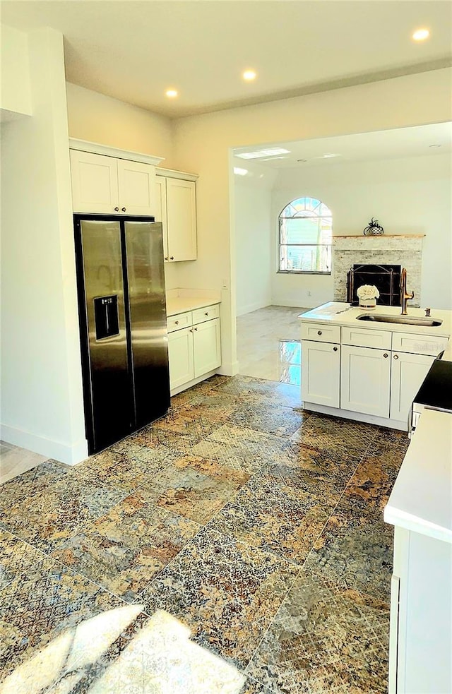 kitchen featuring recessed lighting, white cabinets, fridge with ice dispenser, and a sink