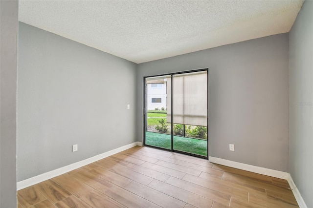 spare room with a textured ceiling and light hardwood / wood-style flooring