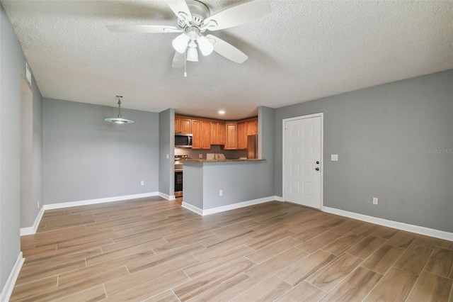 unfurnished living room with ceiling fan and a textured ceiling