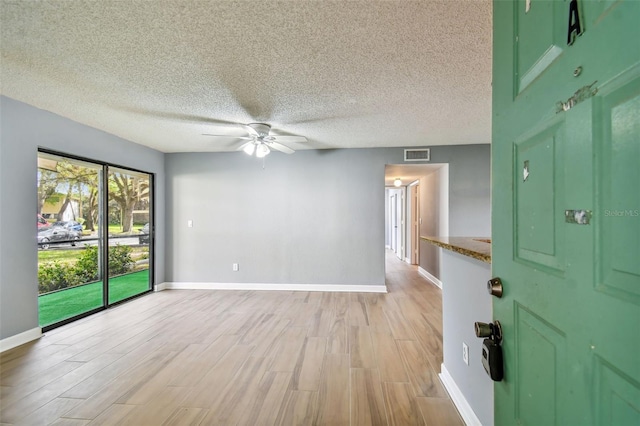 unfurnished room with light wood-type flooring, ceiling fan, and a textured ceiling