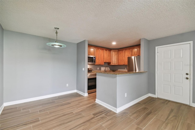 kitchen with stainless steel appliances, decorative light fixtures, a textured ceiling, and kitchen peninsula