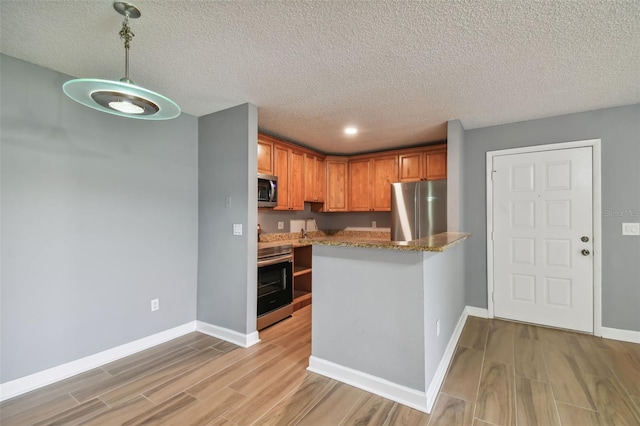 kitchen featuring kitchen peninsula, decorative light fixtures, stainless steel appliances, light wood-type flooring, and sink