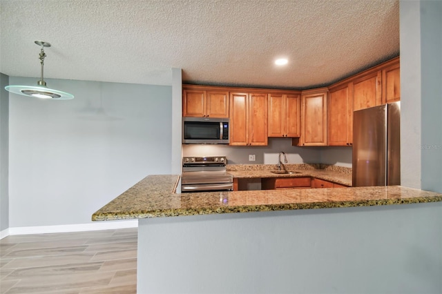 kitchen with stainless steel appliances, sink, a textured ceiling, kitchen peninsula, and light stone countertops