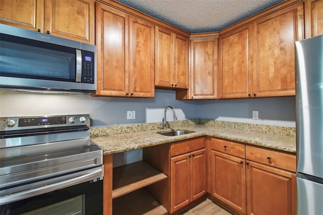 kitchen with light stone counters, stainless steel appliances, and sink