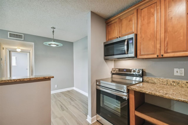 kitchen featuring appliances with stainless steel finishes, hanging light fixtures, light wood-type flooring, light stone countertops, and a textured ceiling