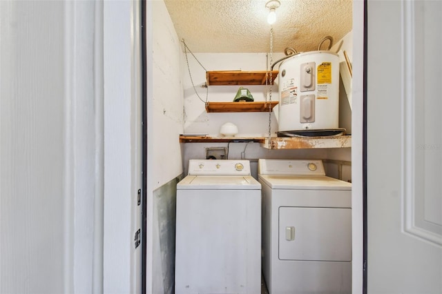 laundry area with a textured ceiling, water heater, and washing machine and clothes dryer