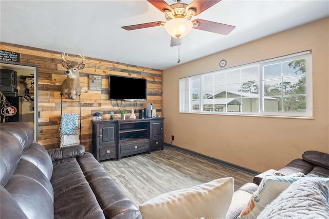 living room featuring hardwood / wood-style flooring, ceiling fan, and wooden walls