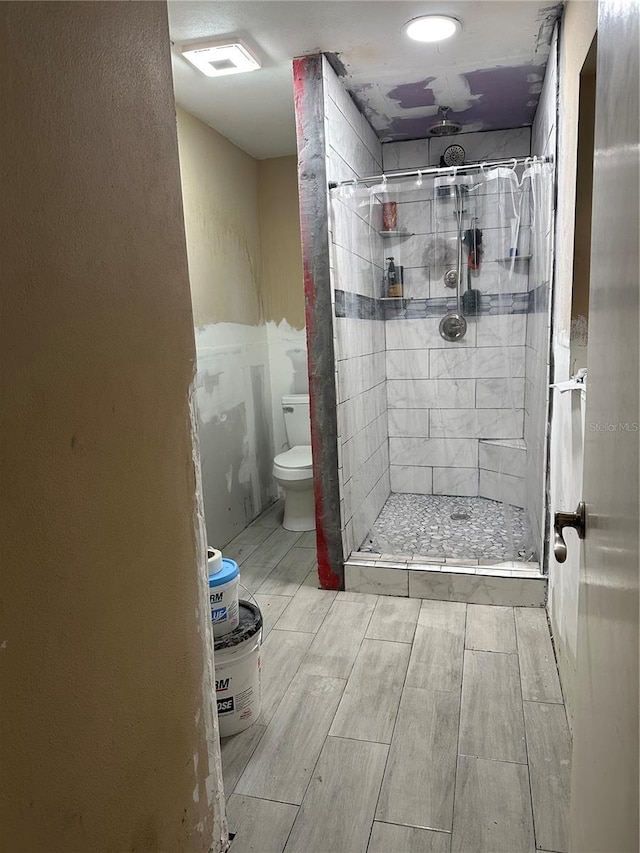 bathroom with a tile shower and toilet