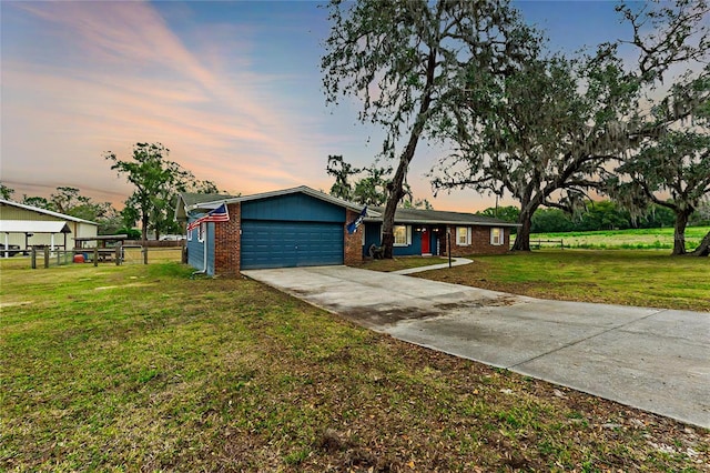 ranch-style house featuring a garage, brick siding, driveway, and a yard