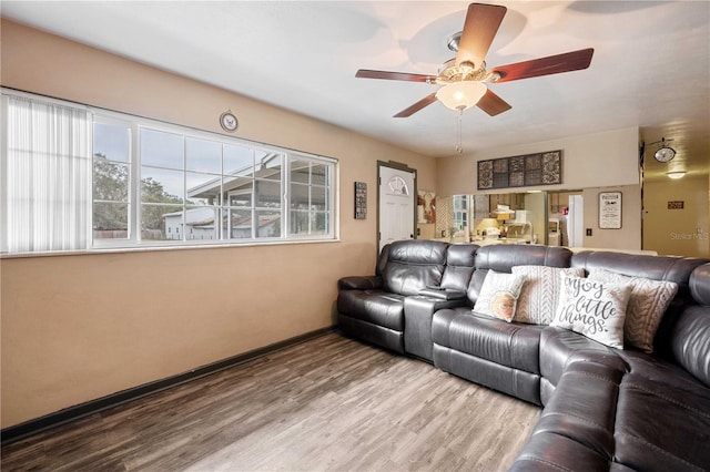 living room featuring a ceiling fan, baseboards, and wood finished floors