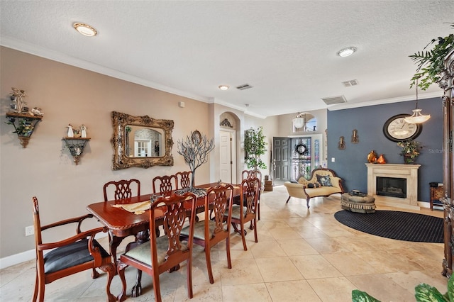 dining area with a textured ceiling, crown molding, and light tile patterned floors