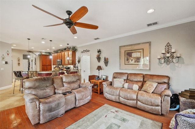 living room with ceiling fan, crown molding, and hardwood / wood-style floors