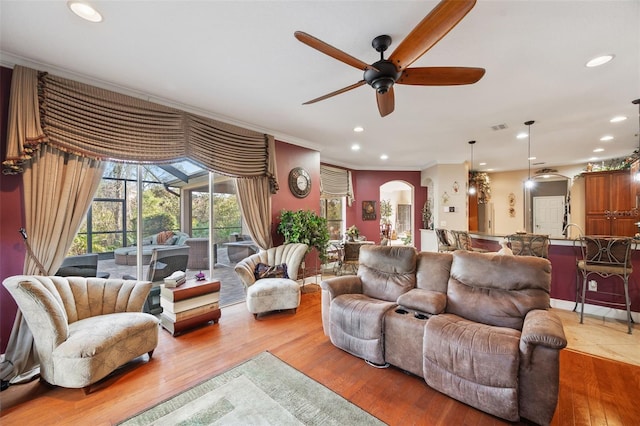 living room featuring ceiling fan, ornamental molding, and light hardwood / wood-style flooring