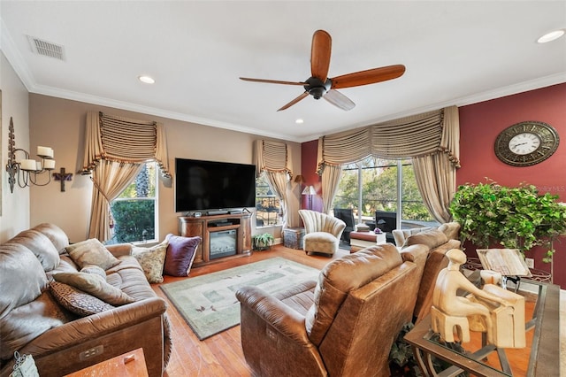 living room with a fireplace, ceiling fan, crown molding, and light hardwood / wood-style flooring