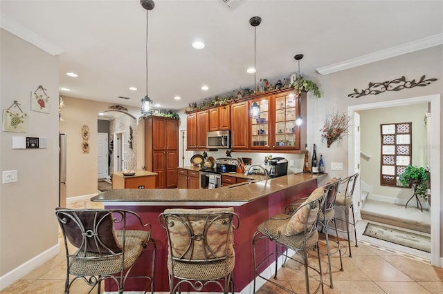 kitchen featuring kitchen peninsula, stainless steel appliances, decorative light fixtures, and a kitchen bar