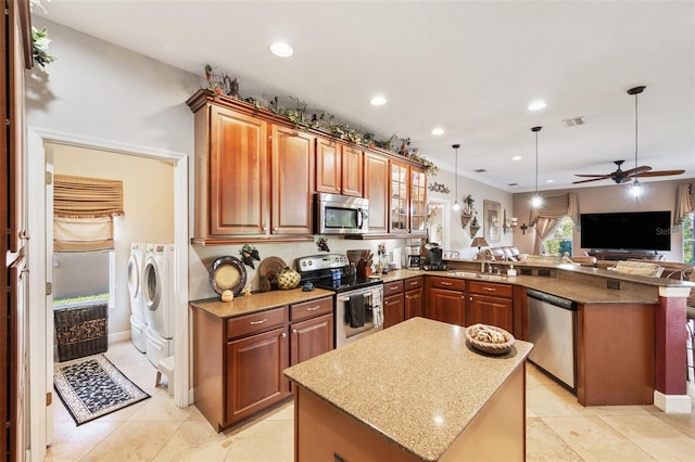 kitchen featuring stainless steel appliances, independent washer and dryer, ceiling fan, kitchen peninsula, and hanging light fixtures