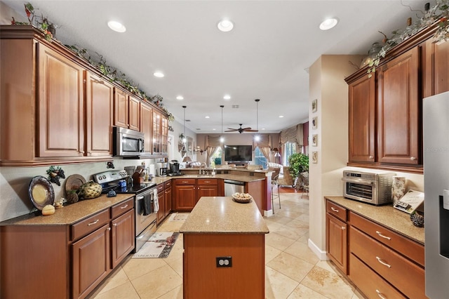 kitchen featuring kitchen peninsula, light stone countertops, a center island, hanging light fixtures, and stainless steel appliances