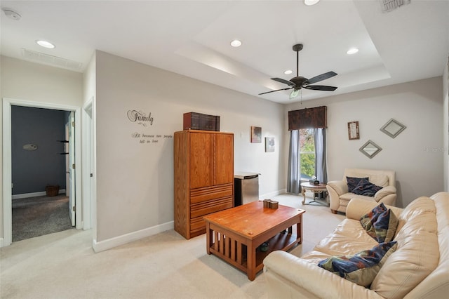 living room featuring light carpet, ceiling fan, and a tray ceiling