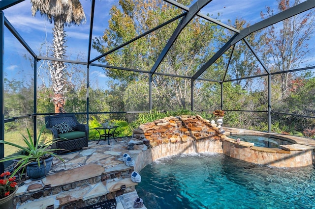 view of pool with a patio area, glass enclosure, pool water feature, and an in ground hot tub