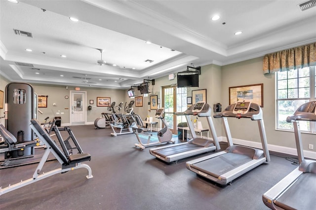 exercise room with crown molding, plenty of natural light, and a tray ceiling