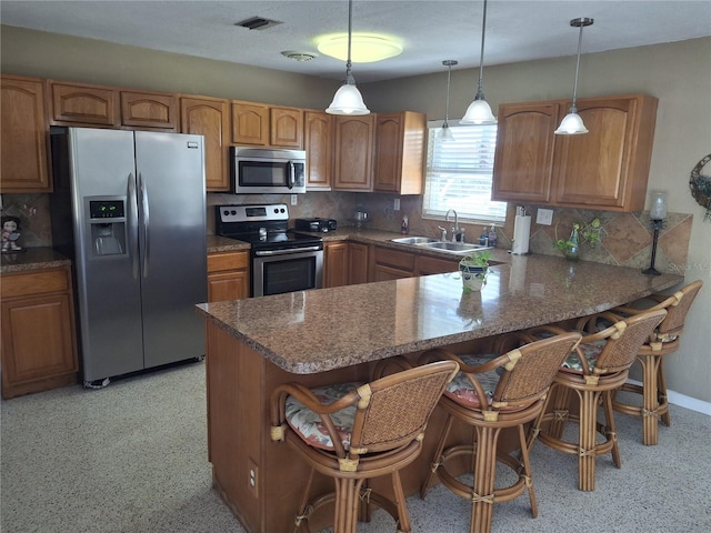 kitchen featuring sink, stainless steel appliances, a kitchen breakfast bar, decorative light fixtures, and kitchen peninsula